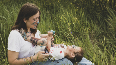 50 € Startprämie fürs Kinderdepot Lachendes Kind mit Farbe im Gesicht auf dem Schoss der Mutter